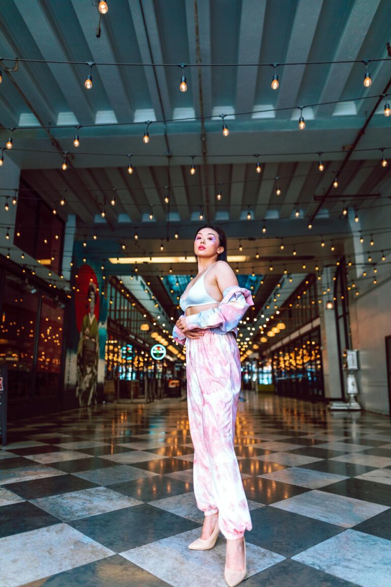 Confident woman in fashionable attire under string lights in an indoor space