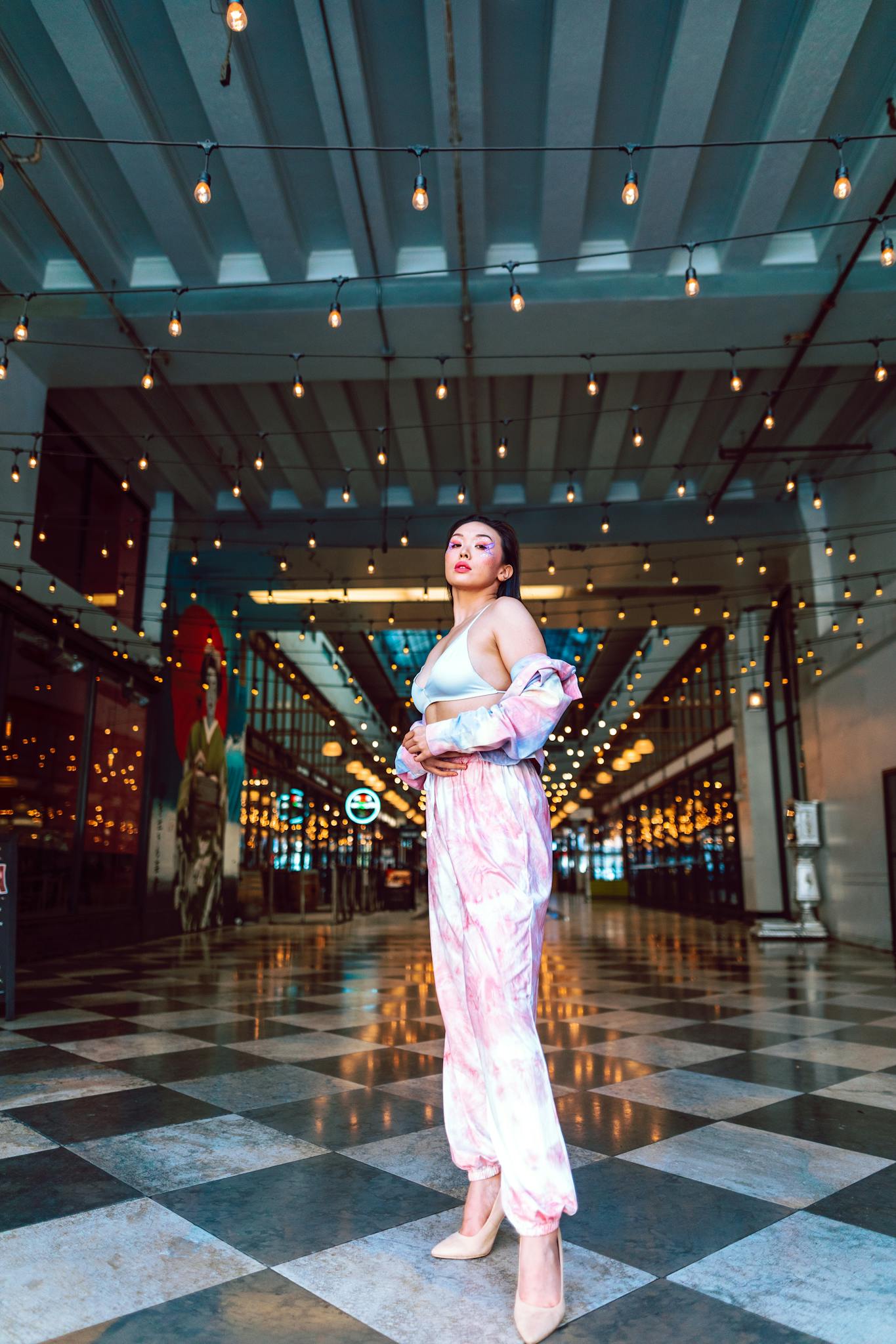 Confident woman in fashionable attire under string lights in an indoor space